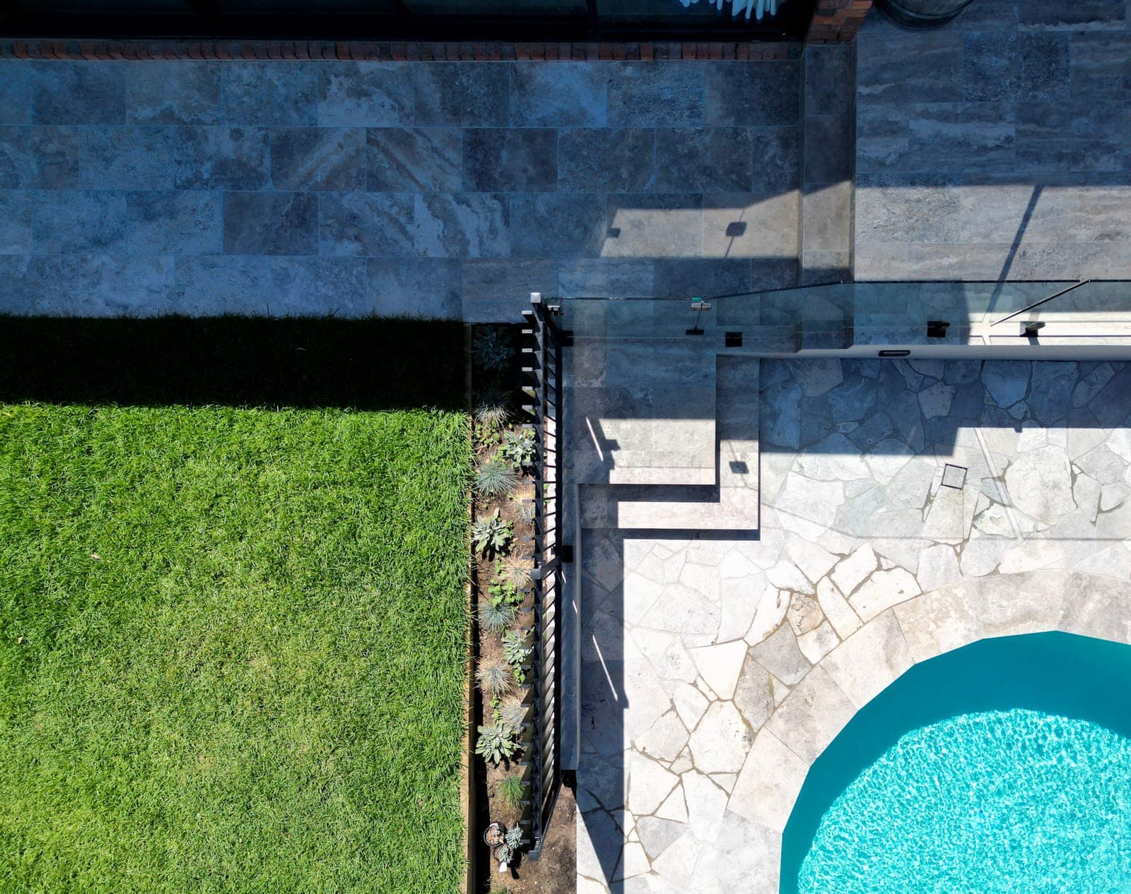 Landscaped lawn, paving and planting beside a pool